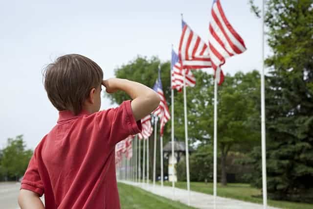 A young boy salutes the flags of a Memorial Day display along a small town street