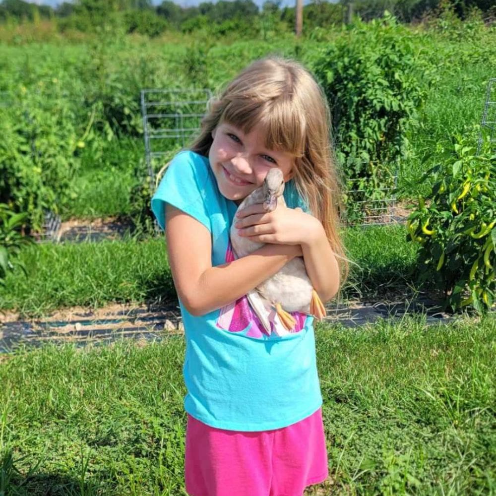 Girl hugging Call Duck with grennery in garden background